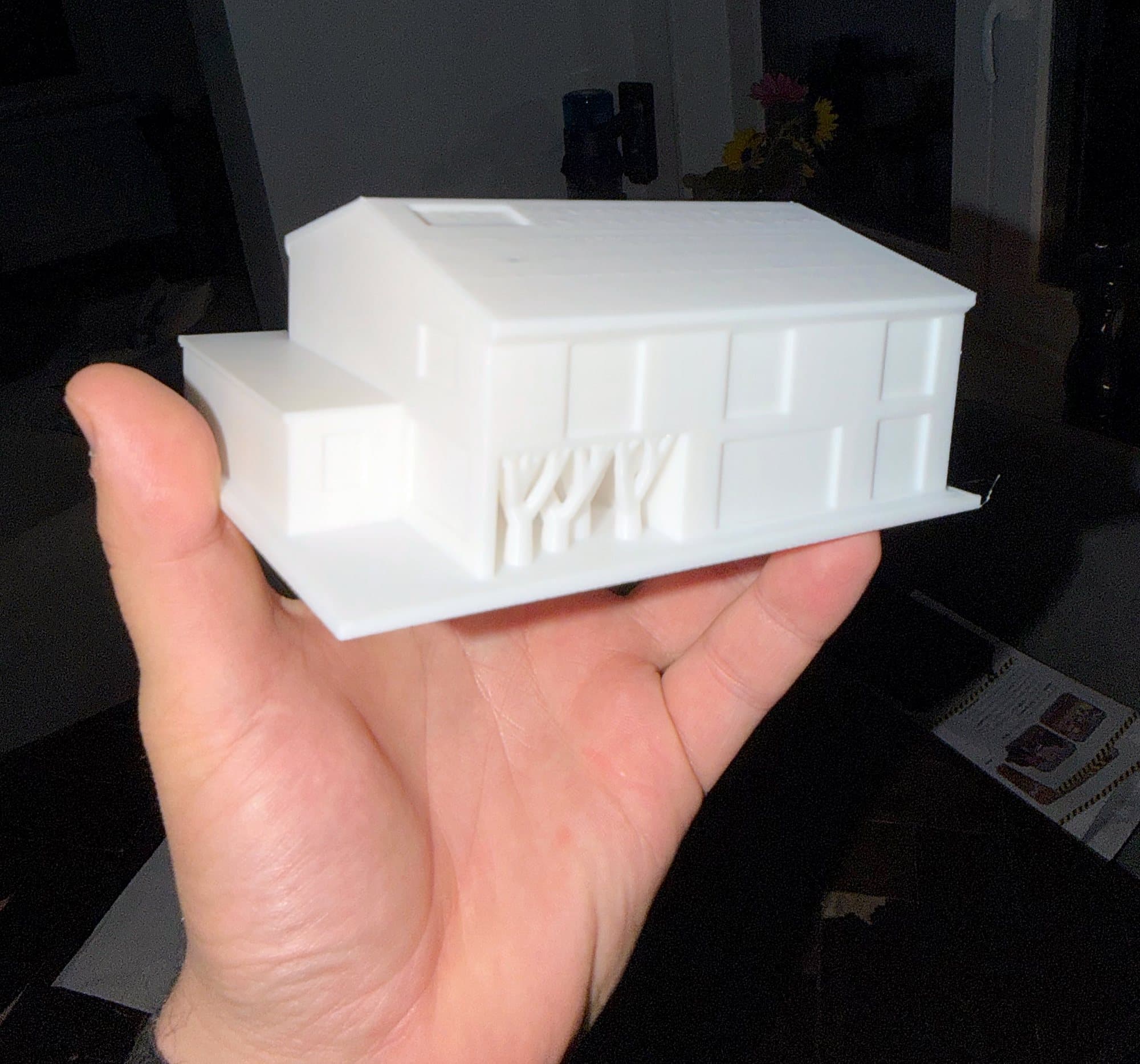Testdruck eines weißen Architekturmodells in einer Hand, Vorderseite.